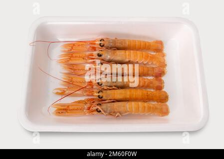 Langostine, scampi crudi pronti per essere cotti in vassoio di plastica alimentare in vendita isolato su bianco, vista dall'alto con percorso di taglio Foto Stock