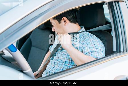 Primo piano di indossare la cintura di sicurezza del conducente. Concetto di un conducente in auto che indossava la cintura di sicurezza. Vista laterale della persona che si mette sulla cintura di sicurezza, felice Foto Stock