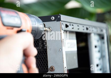 Il tecnico avvita il retro del computer, fissandolo Foto Stock