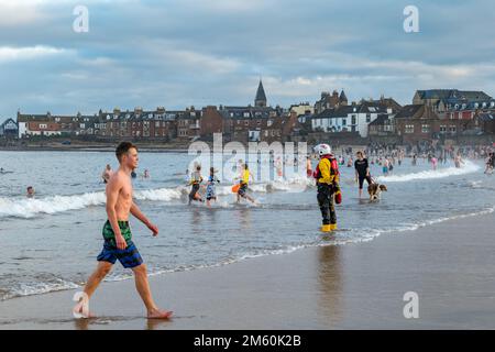 North Berwick, East Lothian, Scotland, UK, 1st gennaio 2023, Loony Dook: Il tuffo annuale nel Firth of Forth a West Bay, nella città balneare, con centinaia di persone che partecipano e l'RNLI a portata di mano per la sicurezza. Il sole è uscito anche durante il tuffo di Capodanno in mare. Credit Sally Anderson/Alamy Live News Foto Stock