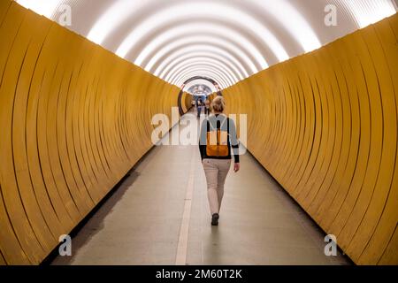 Donna cammina attraverso il tunnel pedonale di Brunkenberg a Stoccolma, Svezia Foto Stock