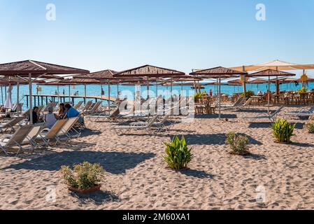 Sedie a sdraio e ombrelloni sono disponibili sulla spiaggia di sabbia durante le giornate di sole Foto Stock