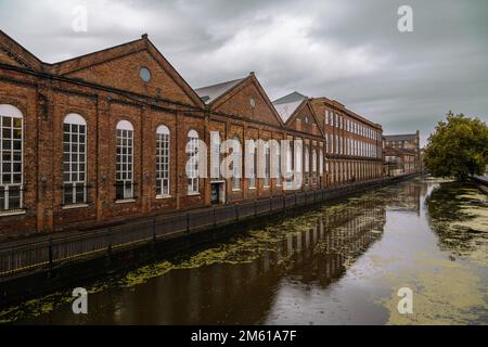 Una fila di vecchi edifici industriali che si trovano lungo un fiume a Waterside, Lincoln. Foto Stock