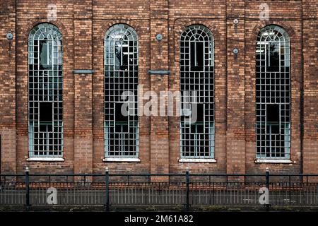 Particolare di alcuni vecchi edifici industriali con alte finestre ad arco. Ingegneria, locali commerciali, officina, concetto di settore. Foto Stock