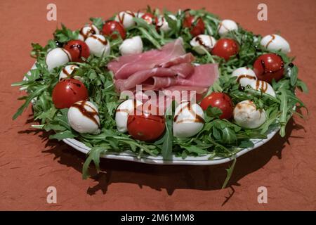 Piatto di sana alimentazione con mozzarella, rucola, prosciutto, pomodori, aceto balsamico e olio d'oliva Foto Stock