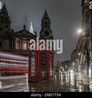 Un autobus di Londra passa davanti a una cassetta telefonica rossa fuori da St Paul a Londra. Foto Stock