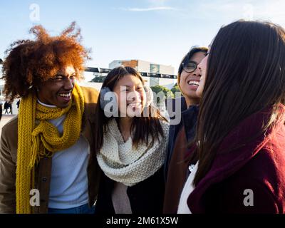 Gruppo di giovani multietnici in abiti invernali che si divertono. Amici degli studenti millenari. Foto Stock