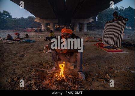 Nuova Delhi, India. 1st Jan, 2023. Un uomo senza casa si riscalda intorno ad un piccolo fuoco in una fredda mattina d'inverno sotto un ponte sulle rive del fiume Yamuna. Con l'inizio del nuovo anno di domenica, la temperatura minima nella capitale nazionale è sceso a 5,5 gradi Celsius, due tacche al di sotto della media stagionale. (Credit Image: © Kabir Jhangiani/ZUMA Press Wire) Foto Stock