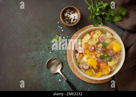 Zuppa tradizionale di cavolo Zelnacka con salsicce e verdure in una ciotola su un tavolo di pietra. Cucina ceca. Vista dall'alto. Spazio di copia. Foto Stock