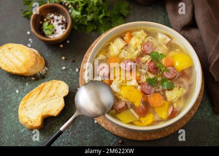 Zuppa tradizionale di cavolo Zelnacka con salsicce e verdure in una ciotola su un tavolo di pietra. Cucina ceca. Foto Stock