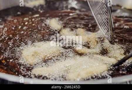 Preparazione di churros fritti con zucchero tipico della Spagna Foto Stock