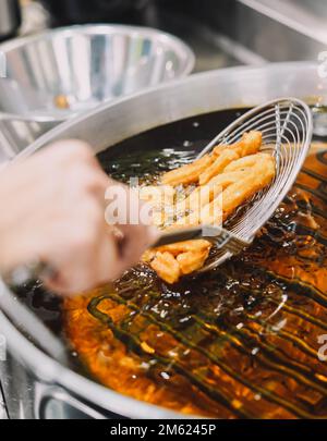 Preparazione di churros fritti con zucchero tipico della Spagna Foto Stock