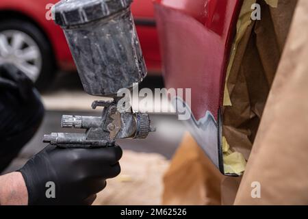 Verniciatura con vernice di fondo danneggiata sul paraurti di un'auto rossa Foto Stock