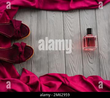 sandali bordeaux zeppa scarpe scialle e bottiglia di profumo rosa. Estate sfondo modello mockup copia spazio libero pattern composizione colorata testo campione Foto Stock