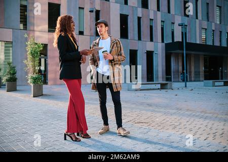 Colleghi aziendali che discutono del lavoro mentre si trovano all'aperto nel quartiere finanziario. Foto Stock