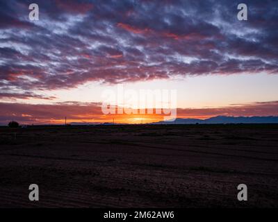 Un luminoso tramonto invernale nel deserto dell'Arizona proietta diverse tonalità vibranti sulle nuvole e sul paesaggio Foto Stock