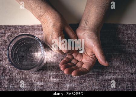 Pillole nelle mani di una vecchia donna, vista dall'alto. Foto Stock