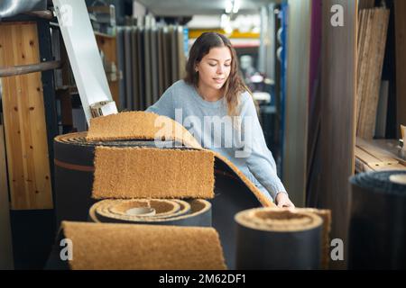 Donna che sceglie i campioni di pavimentazione nell'ipermercato di costruzione Foto Stock