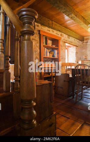 Vecchia scala in legno con palo e ringhiera in newel torniti nella sala da pranzo all'interno di una vecchia casa in pietra di campo in stile cottage del 1850 circa. Foto Stock