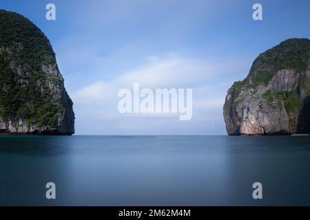 Vista dalla spiaggia Maya che si affaccia sulle scogliere rocciose. La lunga esposizione dà un mare liscio e serico. Foto Stock