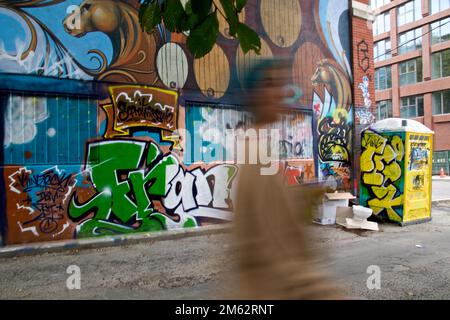 Movimento sfocato di una donna che cammina con lo sfondo graffiti. Foto Stock