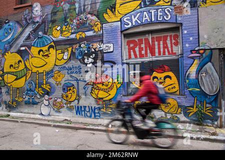 Un uomo in bicicletta con sfondo graffiti. Foto Stock