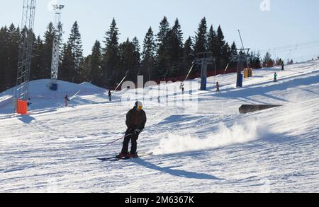 Umea, Norrland Svezia - 19 febbraio 2022: Uomo sciare giù per la collina con lo skilift in background Foto Stock