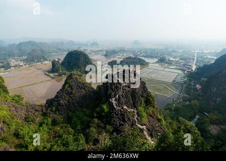 Dall'alto vista panoramica del fiume che scorre attraverso il villaggio e le colline ricoperte di piante verdi nelle giornate di sole in Vietnam Foto Stock