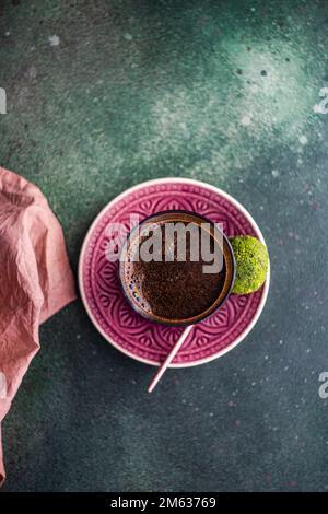 Da sopra un bicchiere di caffè turco e tradizionali pakhlava palle dolci servite su un tavolo di cemento verde Foto Stock