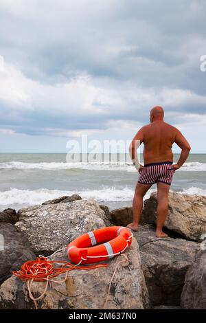 Uomo che guarda il mare dalle rocce Foto Stock