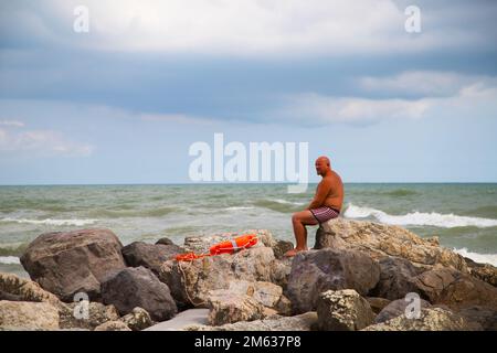 Uomo che guarda il mare dalle rocce Foto Stock