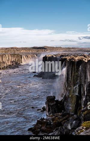 Veduta aerea della cascata Selfoss che cade dalla scogliera rocciosa nel fiume Jokulsa Fjollum sotto il cielo blu con luce solare situato in Islanda Foto Stock