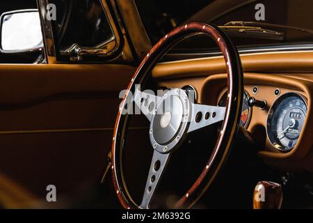 Volante in legno e acciaio in cabriolet di lusso retrò con interni in pelle beige parcheggiato in garage Foto Stock