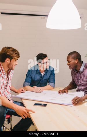 Architetti e ingegneri che lavorano in ufficio seduti in un grande tavolo Foto Stock