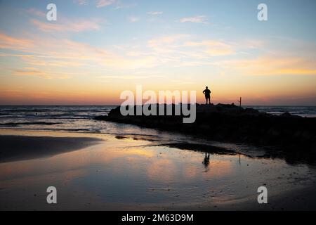L'uomo rilassato osserva il mare dalle rocce Foto Stock