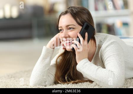 Felice teen parlando al telefono sul pavimento a casa Foto Stock