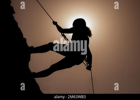 Silhouette di successo giovane arrampicatore femminile in montagna concetto di auto-miglioramento, motivazione, ispirazione movimento, obiettivi motivazionali. Foto Stock