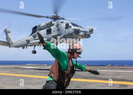 SOUTH CHINA SEA (30 marzo 2022) Aviation Structural Mechanic Airman Keller Curry, di Wasilla, Alaska, segnala un elicottero MH-60R Sea Hawk, assegnato ai 'Raptors' di Helicopter Maritime Strike Squadron (HSM) 71, per lanciare dal ponte di volo della portaerei di classe Nimitz USS Abraham Lincoln (CVN 72). Abraham Lincoln Strike Group è in fase di implementazione pianificata nell'area delle operazioni della flotta 7th degli Stati Uniti per migliorare l'interoperabilità attraverso alleanze e partnership e al tempo stesso fungere da forza di risposta pronta a sostegno di una regione indomPacifico libera e aperta. Foto Stock