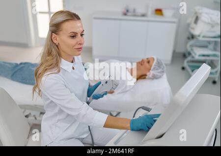 Ritratto di giovane cosmetologo che tiene attrezzature per la rimozione dei capelli laser Foto Stock