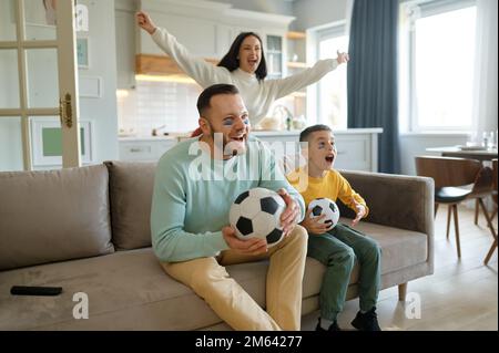 Genitore eccitato con bambino overjoyed che guarda la partita di calcio in tv a casa Foto Stock