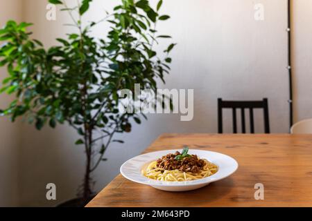 Spaghetti bolognesi in un piatto bianco su un tavolo di legno. Un piatto classico di cucina italiana. Foto Stock