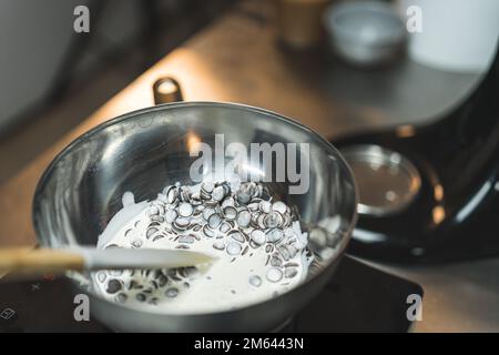 Colpo di primo piano di gocce di cioccolato fondenti con panna pesante su acqua bollente. Sfondo sfocato. Foto di alta qualità Foto Stock