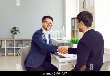 La gente soddisfatta di affari che scuote le mani dopo la firma del contratto nell'ufficio moderno. Foto Stock