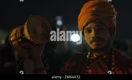 Un uomo indiano che tiene un tamburo mentre sorride Foto Stock