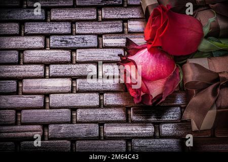 Rose profumate naturali imballate presenti scatole su tappeto di legno di vimini. Foto Stock