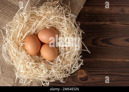 Fieno con uova su sfondo di legno Foto Stock