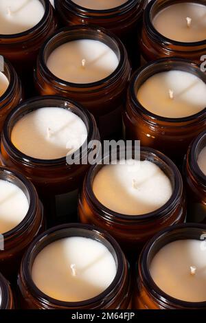 Gruppo di candele di soia e cera di cocco fatte a mano in un contenitore ambrato e opaco, vaso di vetro marrone. Candele naturali ecologiche biologiche. Concetto alla moda Foto Stock