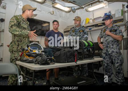 SYDNEY (31 marzo 2022) Navy Diver 2nd Class Corey Astol-malave, di Ceiba, Porto Rico, assegnato al tender sottomarino Emory S. Terra-classe USS Frank Cable (COME 40), spiega le capacità di immersione della nave ai membri della Royal Australian Navy durante un tour della nave a Sydney, 31 marzo. Frank Cable è in pattuglia che conduce la manutenzione e la logistica di spedizione a sostegno della sicurezza nazionale nella zona di funzionamento della flotta degli Stati Uniti 7th. Foto Stock