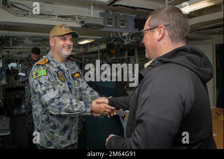 Viktor Pilicic, ufficiale comandante di HMAS Kuttabul, scuote le mani con il comandante militare Sealift capitano del servizio civile Charles Black, maestro dell'asta sottomarina di classe terrestre USS Frank Cable (AS 40), durante un tour della nave a Sydney, marzo 31 2022 31. Frank Cable è in pattuglia che conduce la manutenzione e la logistica di spedizione a sostegno della sicurezza nazionale nella zona di funzionamento della flotta degli Stati Uniti 7th. Foto Stock