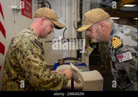 SYDNEY (31 marzo 2022) Hull Technician 1st Class Chad Fry, assegnato alla gara sottomarina di Emory S. Land-class USS Frank Cable (COME 40), spiega le capacità di riparazione della nave al Royal Australian Navy Capt. Viktor Pilicic, comandante di HMAS Kuttabul, durante un tour della nave a Sydney, marzo 31. Frank Cable è in pattuglia che conduce la manutenzione e la logistica di spedizione a sostegno della sicurezza nazionale nella zona di funzionamento della flotta degli Stati Uniti 7th. Foto Stock